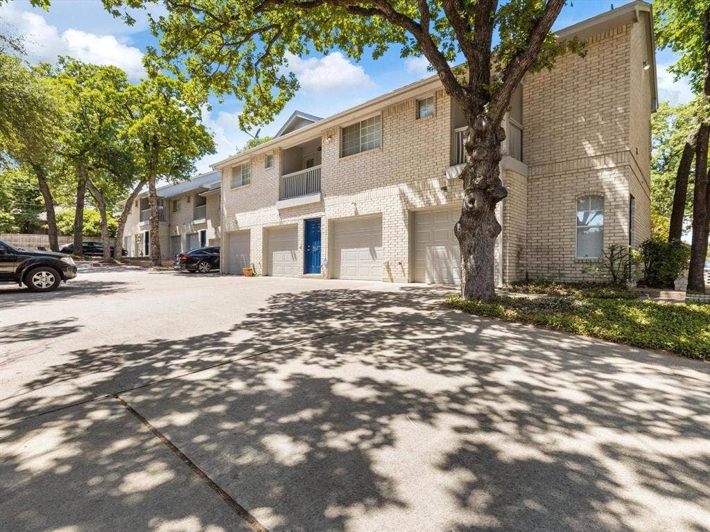 1501 Cedar Elm Drive, #102, Euless, TX 76039 Brick exterior with individual garages, mature trees, and concrete paving