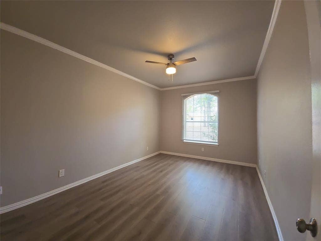 1501 Cedar Elm Drive, #102, Euless, TX 76039 Neutral wall paint, wood-finish flooring, ceiling fan with integrated lighting, window with blinds, and white crown molding
