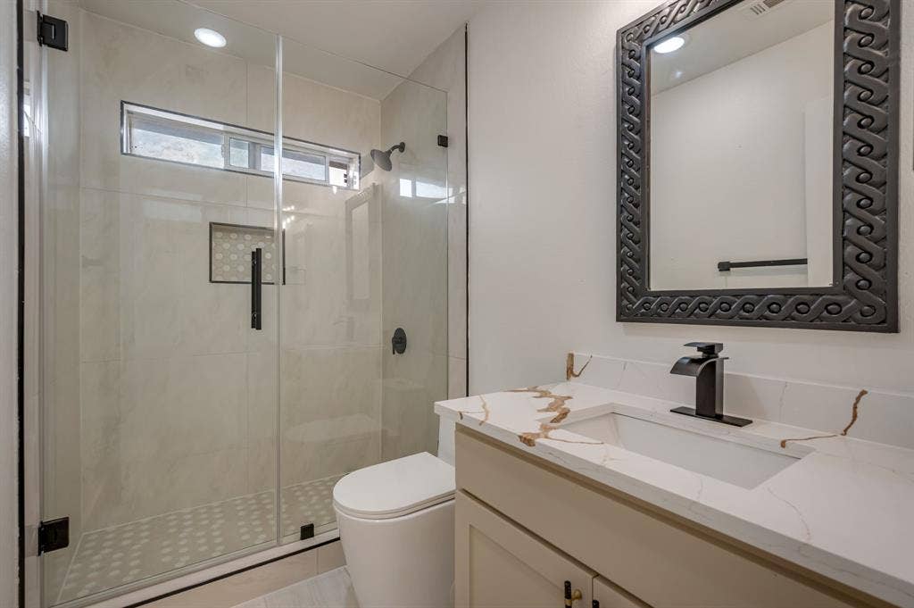 7904 Blacktail Trail, McKinney, TX 75070 Walk-in shower with clear glass enclosure, transom window, and tiled accent niche