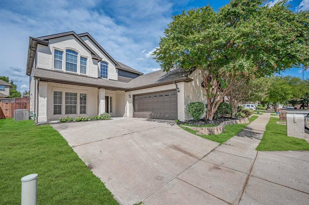 7904 Blacktail Trail, McKinney, TX 75070 Two-story exterior with Beige brick, dark trim, a two-car garage, established landscaping, and a concrete driveway