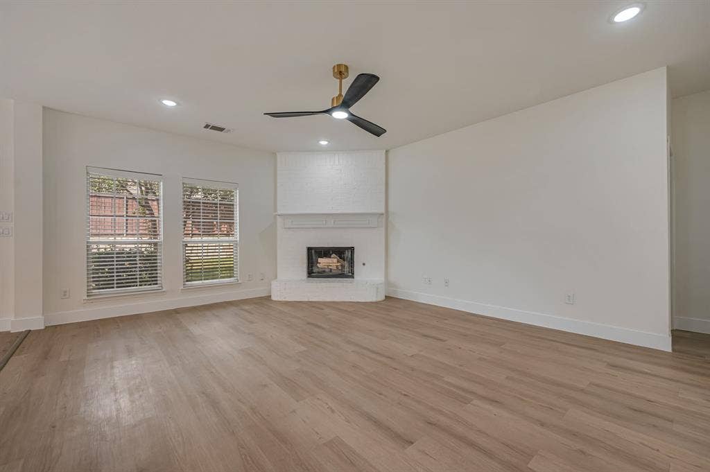 7904 Blacktail Trail, McKinney, TX 75070 Luxury Vinyl Plank flooring, brick fireplace with mantel, recessed lighting, ceiling fan, and multiple windows