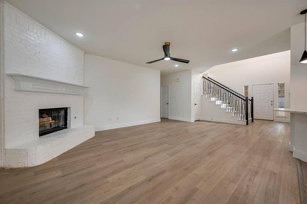 7904 Blacktail Trail, McKinney, TX 75070 Spacious living area featuring Luxury Vinyl Plank flooring, a white-painted brick fireplace with mantel, a modern ceiling fan, and recessed lighting