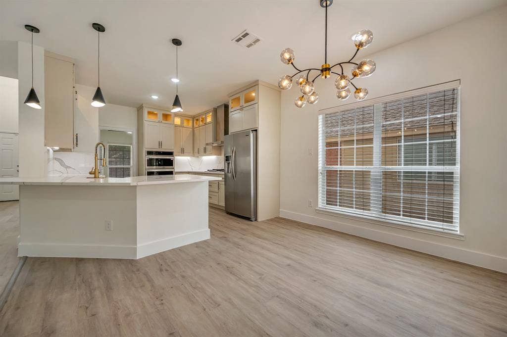 7904 Blacktail Trail, McKinney, TX 75070 Kitchen featuring a gold vein quartz island, stainless steel appliances, light Luxury Vinyl Plank flooring, recessed lighting, and a contemporary chandelier