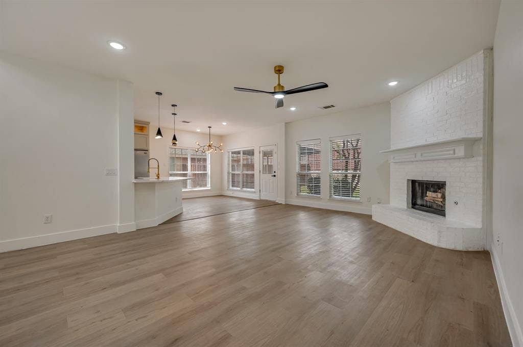 7904 Blacktail Trail, McKinney, TX 75070 Expansive living area with Luxury Vinyl Plank flooring, recessed lighting, and a corner brick fireplace with a mantle