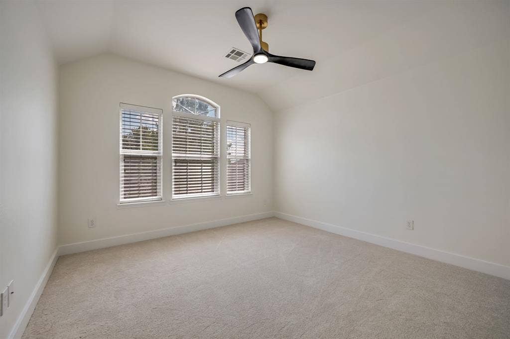 7904 Blacktail Trail, McKinney, TX 75070 Vaulted ceiling, arched window detail, light-colored carpeting, multiple windows with blinds, and a modern ceiling fan