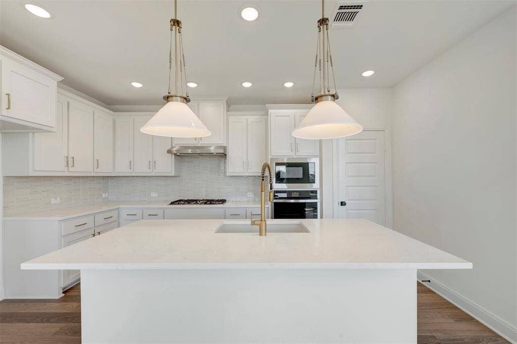 1616 Compass Heights, Mesquite, TX 75181 Kitchen featuring a center island with sink, white cabinetry, integrated stainless steel appliances, and wood-finish flooring