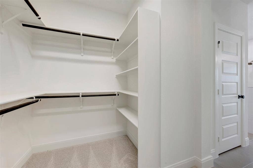 1616 Compass Heights, Mesquite, TX 75181 Walk-in closet featuring extensive shelving, multiple hanging rods, and light-toned carpeting