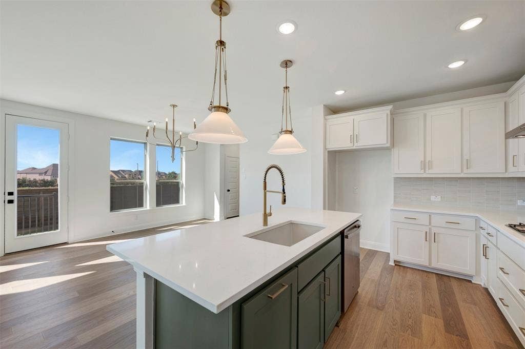 1616 Compass Heights, Mesquite, TX 75181 Kitchen featuring an island with a vessel sink and dual pendant lighting, white upper and lower cabinetry, white countertops, and a tiled backsplash