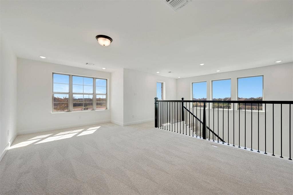 1616 Compass Heights, Mesquite, TX 75181 Expansive open loft area featuring light gray carpeting, multiple windows, recessed lighting, and a contemporary black metal railing