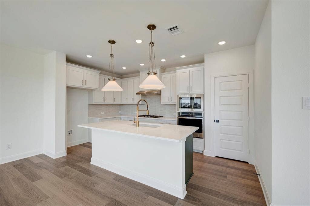 1616 Compass Heights, Mesquite, TX 75181 Gourmet kitchen featuring white shaker cabinetry, an island with a light-colored countertop, recessed lighting, and wood-finish flooring