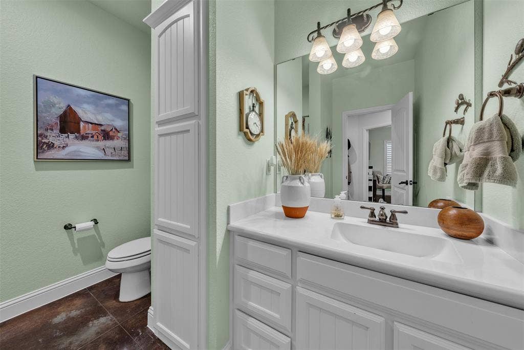 White vanity with an integrated sink and bronze-finish faucet, under a large mirror with a five-light fixture