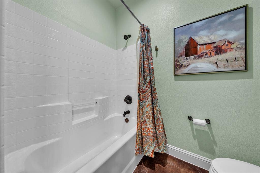 White subway tile shower surround with integrated shelving, dark bronze fixtures, and wood-finish flooring