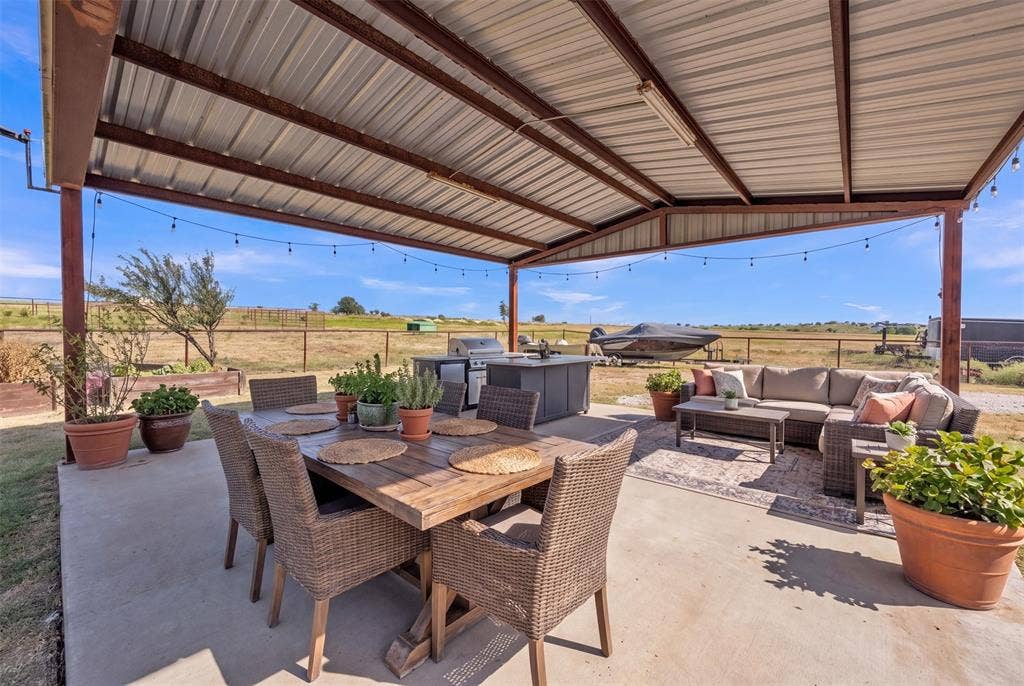 Expansive covered patio with a metal roof structure, concrete flooring, and an integrated outdoor kitchen space