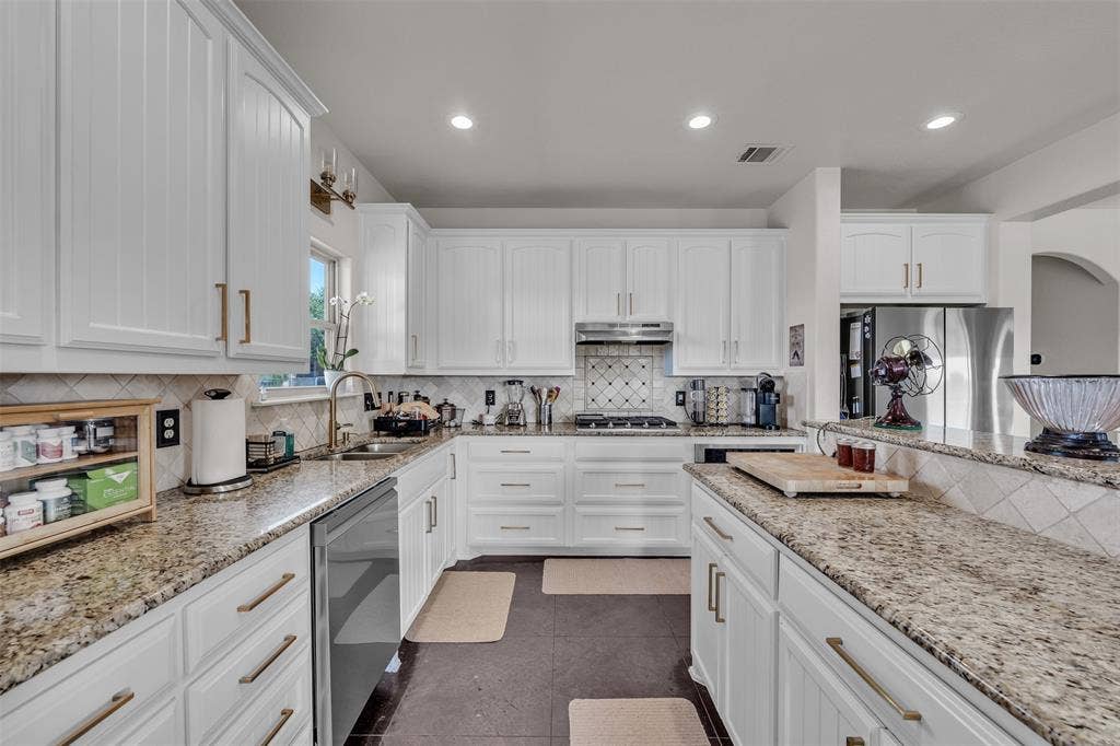 Kitchen featuring white cabinetry, stone countertops, stainless steel appliances, a tile backsplash, and recessed lighting