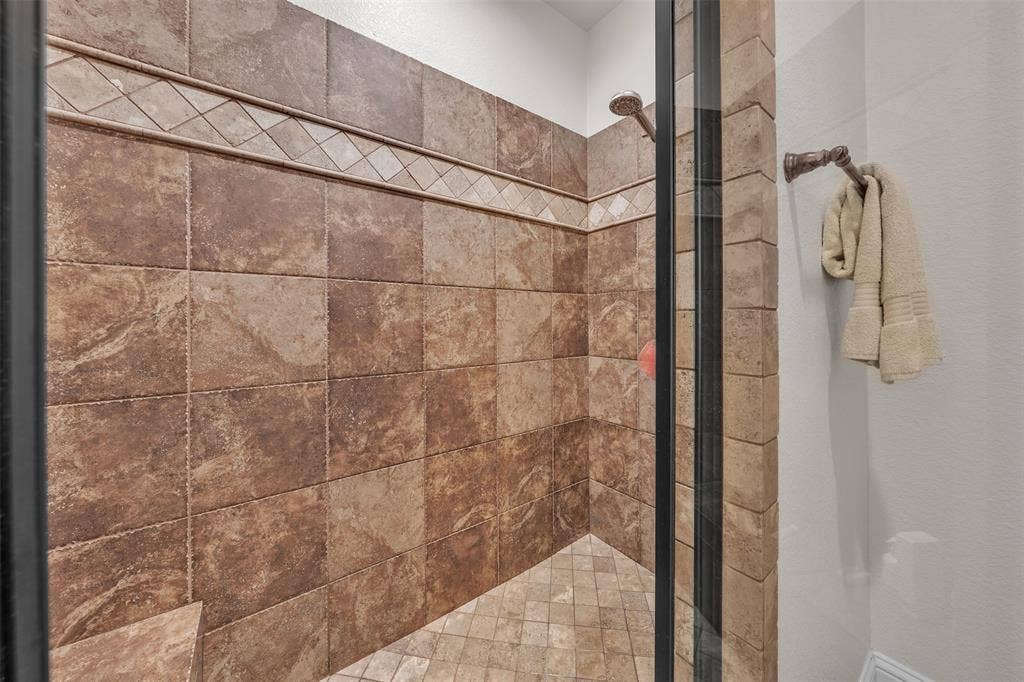 Tiled shower enclosure featuring a decorative accent band and glass door