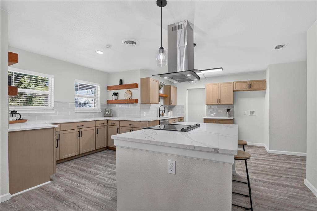 1204 Loma Alta Place, Cleburne, TX 76033 Kitchen featuring an island with a built-in cooktop, a stainless steel range hood, light wood-finish cabinetry, white subway tile backsplash, and wood-finish flooring