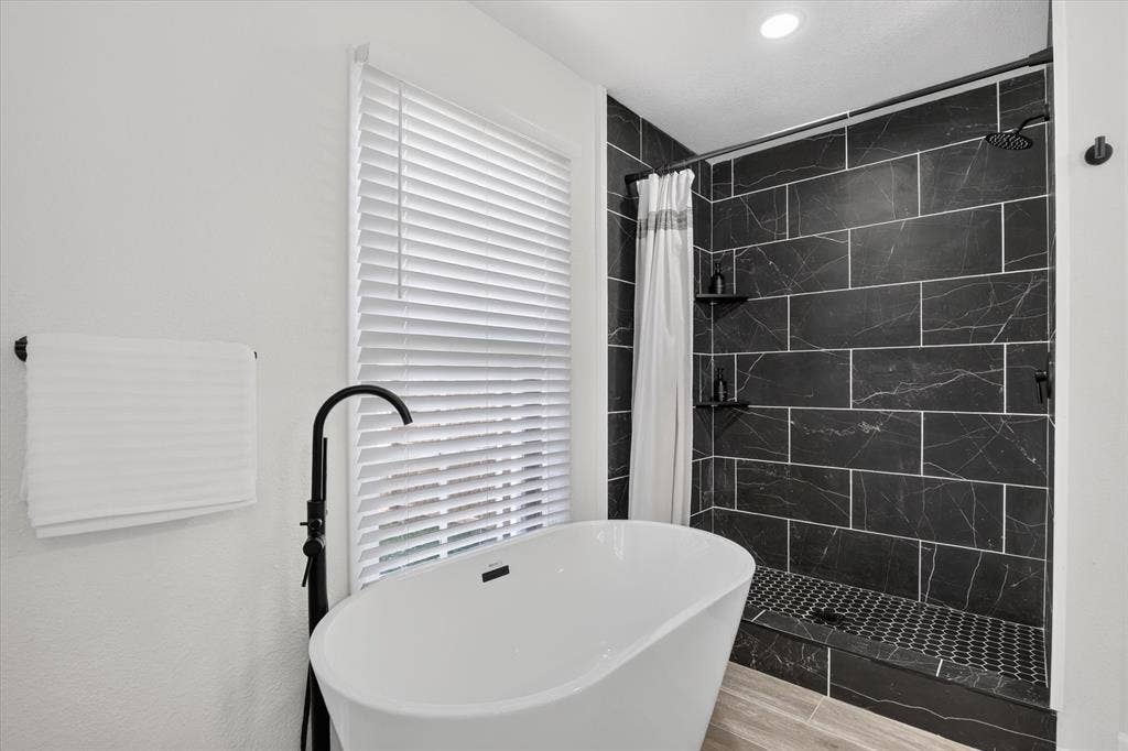 1204 Loma Alta Place, Cleburne, TX 76033 Freestanding soaking tub with a floor-mounted faucet, complemented by a walk-in shower featuring dark subway tile and a dark hexagon tile shower pan