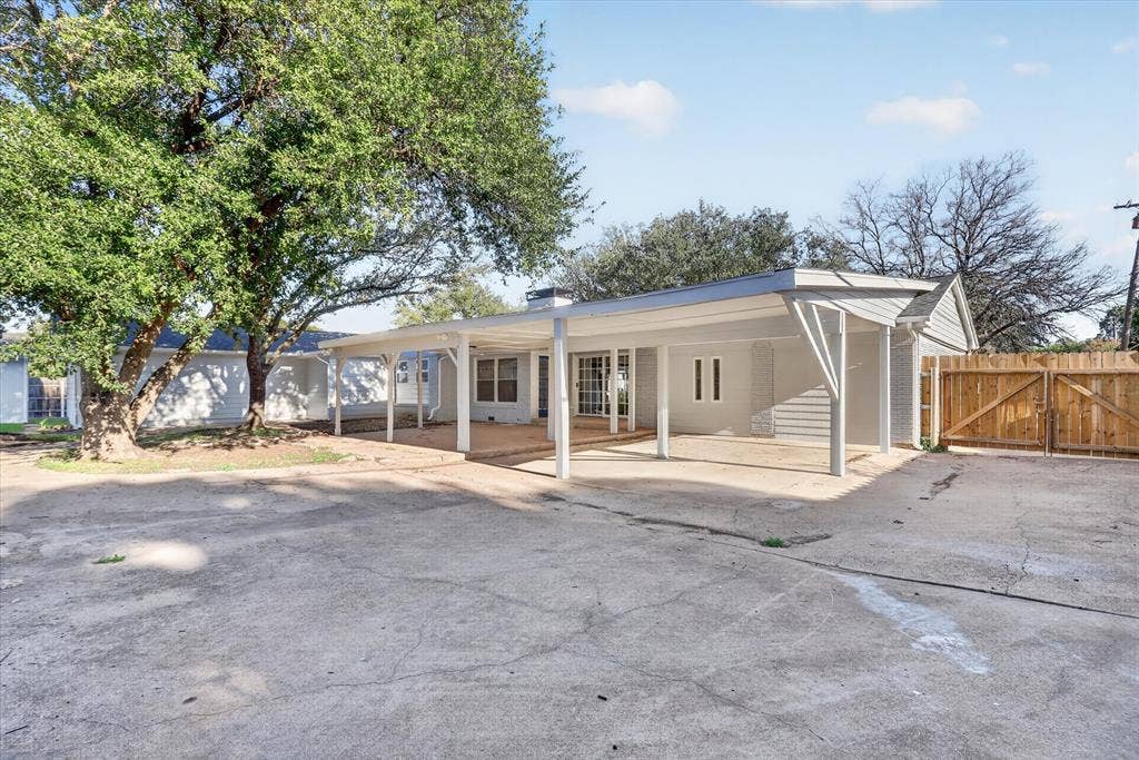 1204 Loma Alta Place, Cleburne, TX 76033 Expansive concrete patio with a covered section, mature trees, and a wood fence