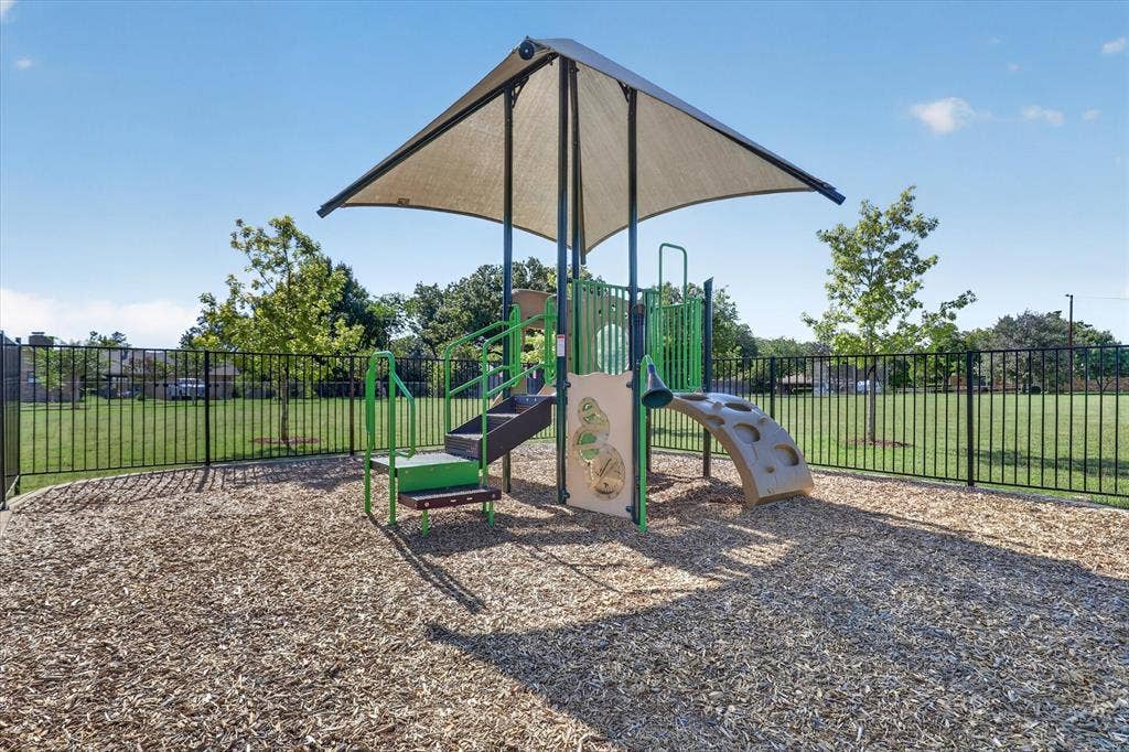1204 Loma Alta Place, Cleburne, TX 76033 Recreational playground structure featuring a shade canopy, steps, climbing elements, and wood chip surfacing