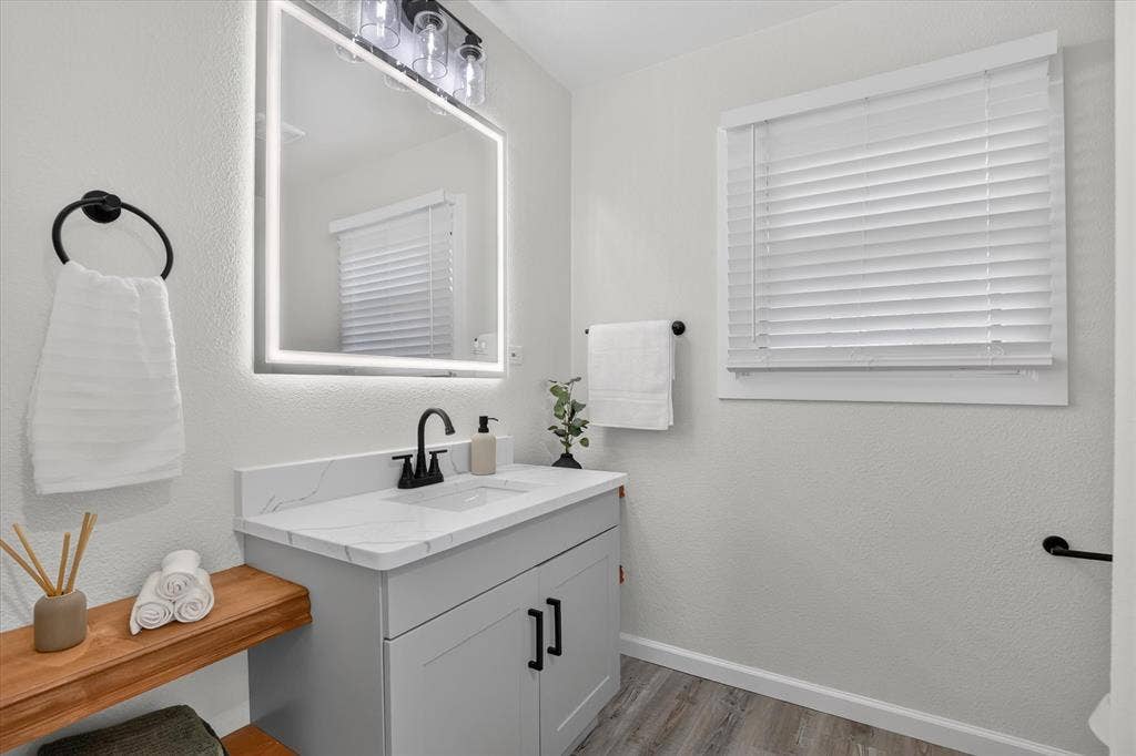 1204 Loma Alta Place, Cleburne, TX 76033 Modern bathroom featuring a floating vanity with wood-finish shelving, white quartz countertop, and matte black hardware