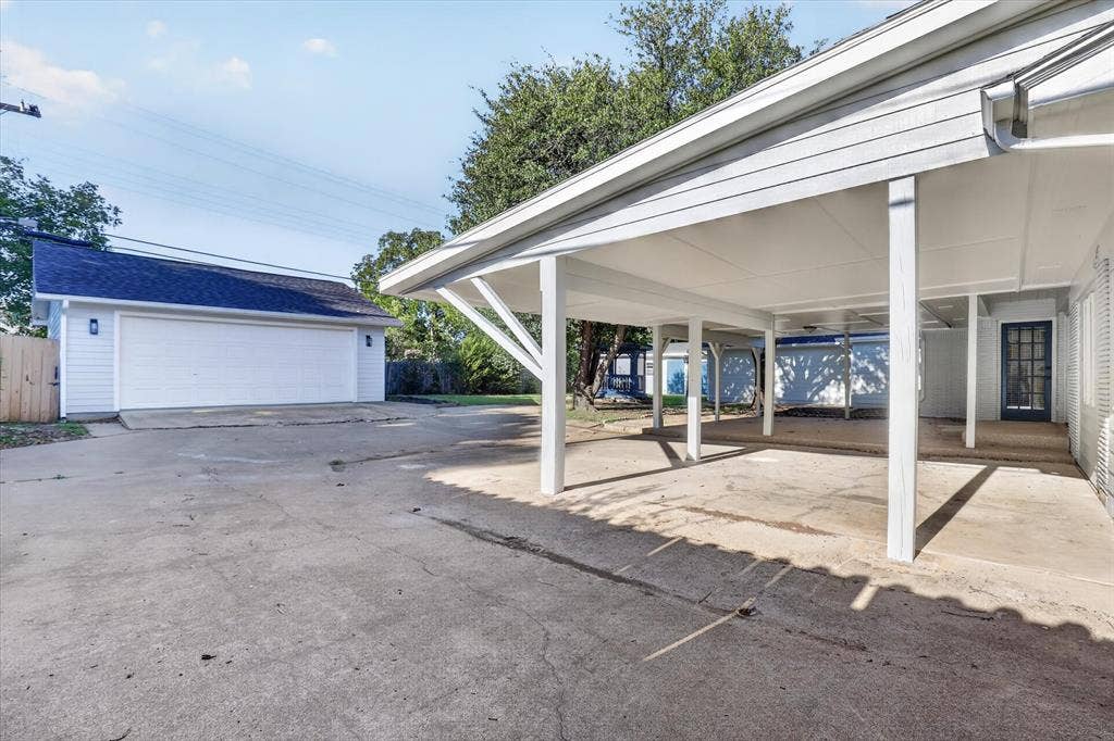 1204 Loma Alta Place, Cleburne, TX 76033 Detached garage with white siding and a dark roof, featuring a double garage door and exterior sconces