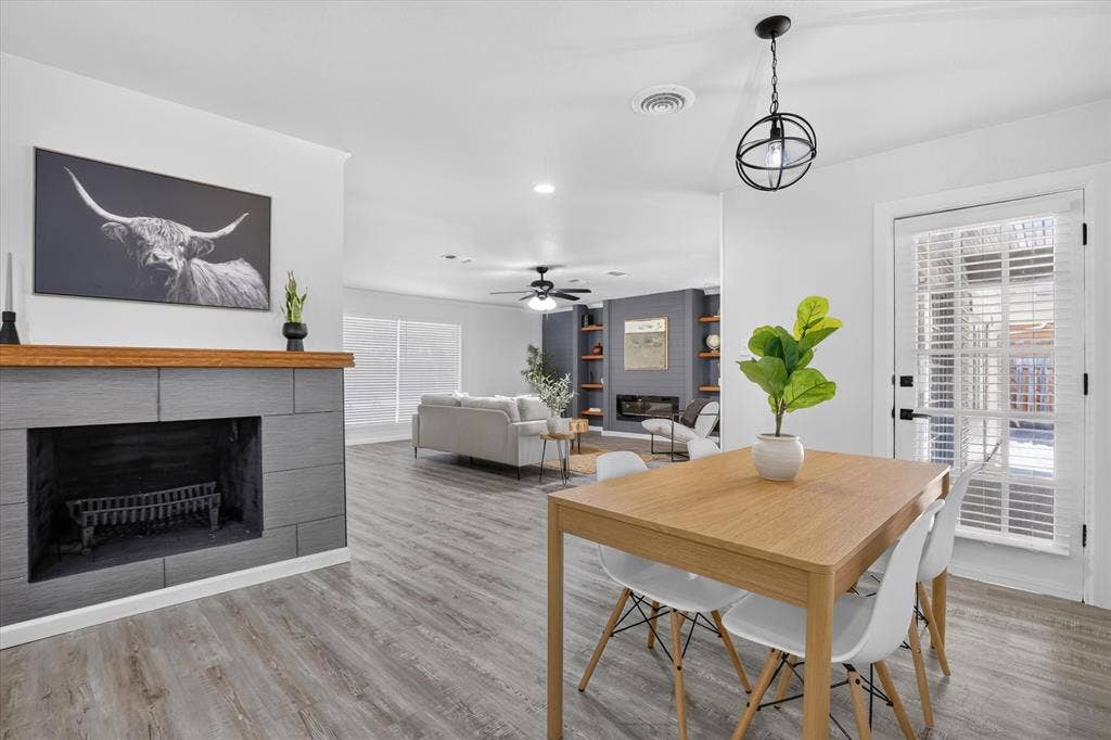 1204 Loma Alta Place, Cleburne, TX 76033 Light wood-finish dining table with a black orb pendant light, wood-finish flooring, and a fireplace with a wood mantel