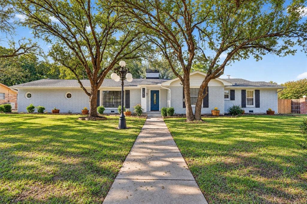 1204 Loma Alta Place, Cleburne, TX 76033 Light gray brick exterior with black shutters and a prominent blue entry door