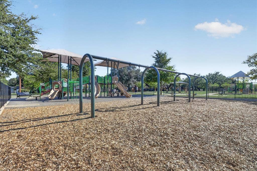 1204 Loma Alta Place, Cleburne, TX 76033 Playground featuring multiple slides, climbing structures, and protective overhead canopies, set on a wood chip surface