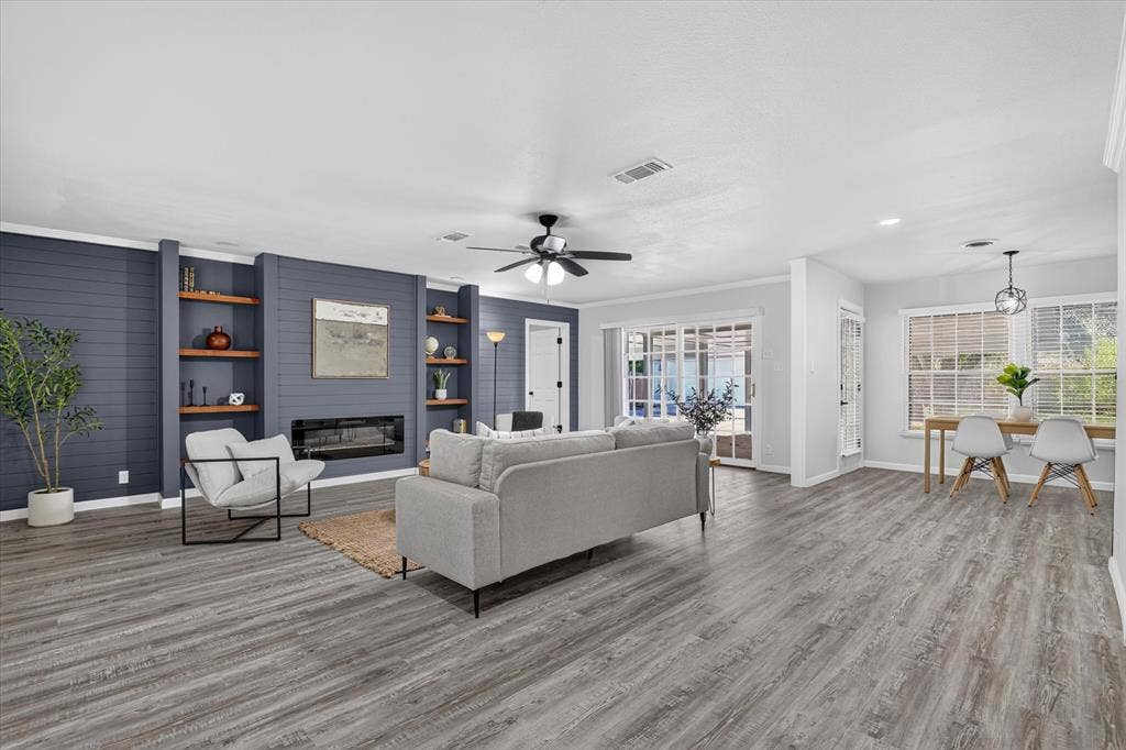 1204 Loma Alta Place, Cleburne, TX 76033 Wood-finish flooring throughout, living space with built-in shelving, electric fireplace, and ceiling fan