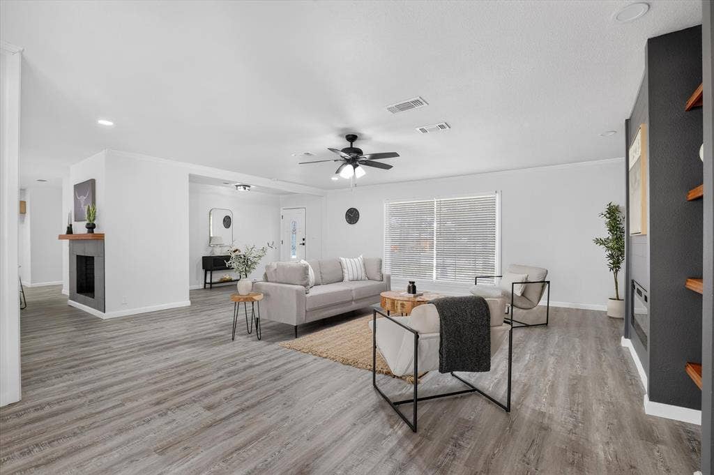1204 Loma Alta Place, Cleburne, TX 76033 Spacious living area featuring wood-finish flooring, a ceiling fan, and a built-in fireplace with a wood mantle