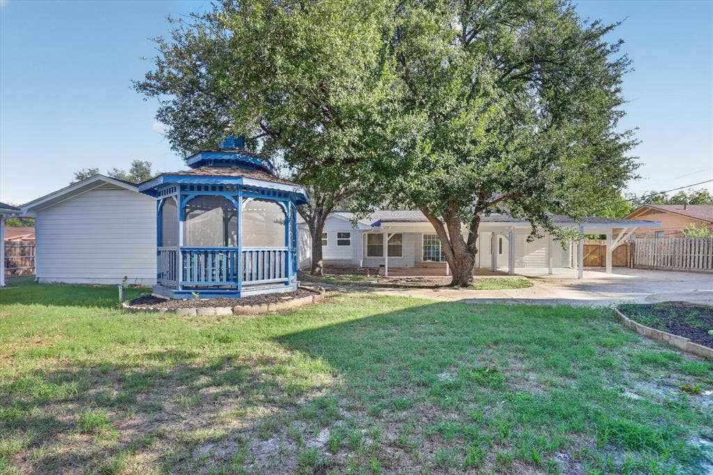 1204 Loma Alta Place, Cleburne, TX 76033 Expansive backyard featuring a blue gazebo, mature trees, and a covered carport