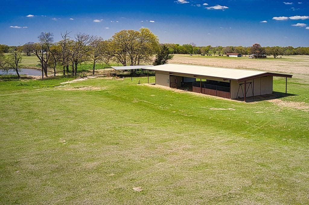 00 Tx-274 Highway, Kemp, TX 75143 Expansive green pasture with a rectangular outbuilding featuring a shed roof, enclosed stalls, and an open-air extension