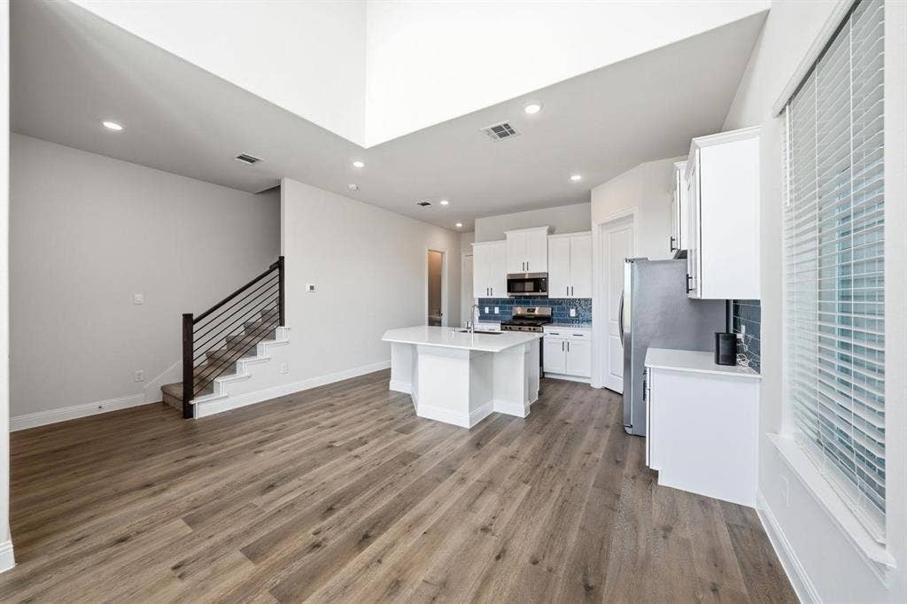 4532 Community Court, Plano, TX 75024 Vaulted ceiling, recessed lighting, wood-finish flooring, kitchen island with built-in cabinetry, and a subway tile backsplash