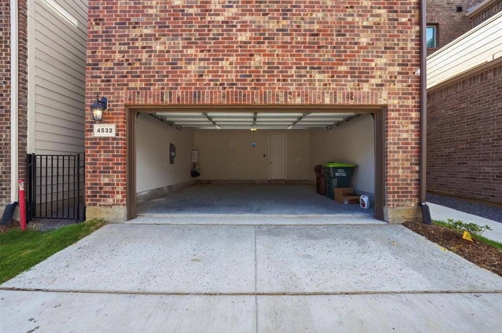 4532 Community Court, Plano, TX 75024 Brick exterior with an attached garage, featuring a metal garage door and a concrete driveway