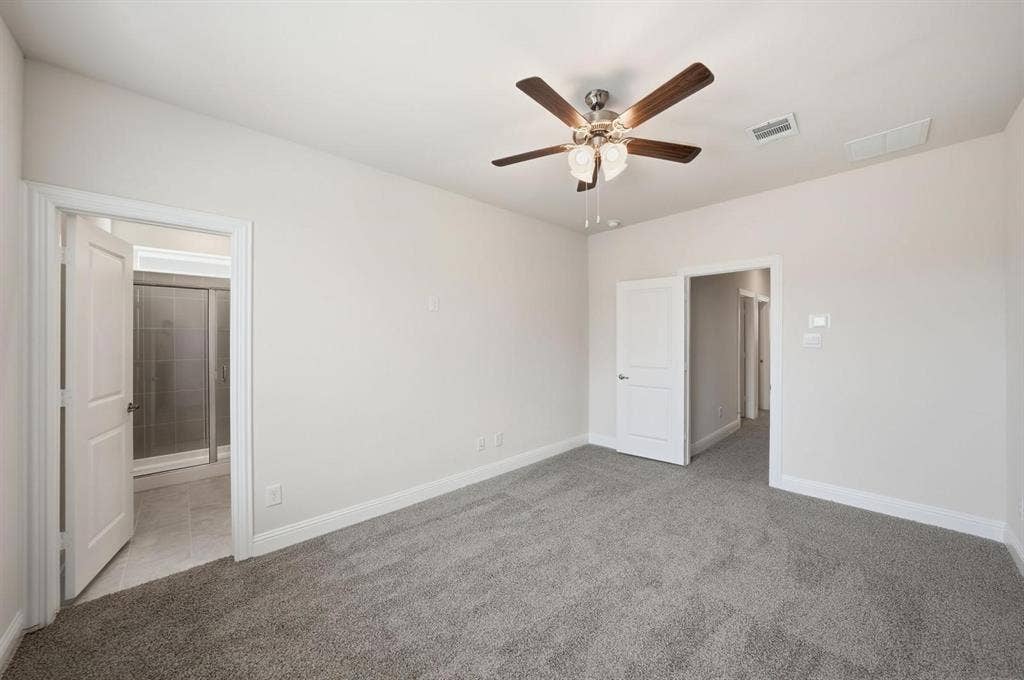 4532 Community Court, Plano, TX 75024 Gray carpet flooring, light neutral wall paint, wood-finish ceiling fan with integrated lighting, white interior doors, and a partial view of a bathroom with a glass-enclosed shower
