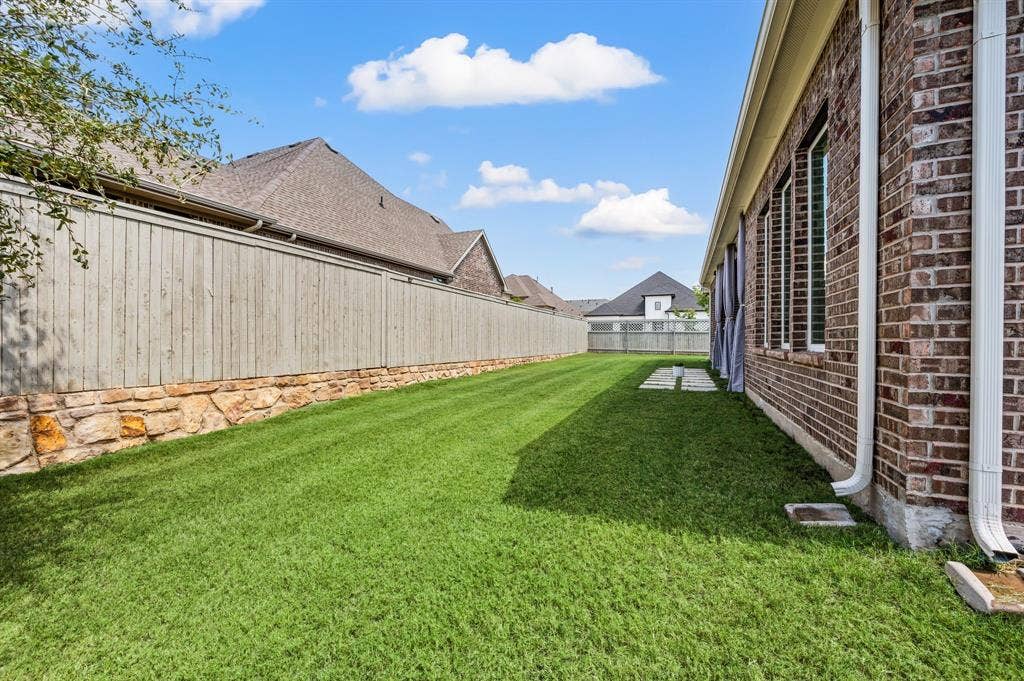 2900 Peekaboo Lane, Northlake, TX 76247 Expansive lawn area featuring a stone and wood privacy fence, and some stone pavers to even extend the patio out a little bit more!