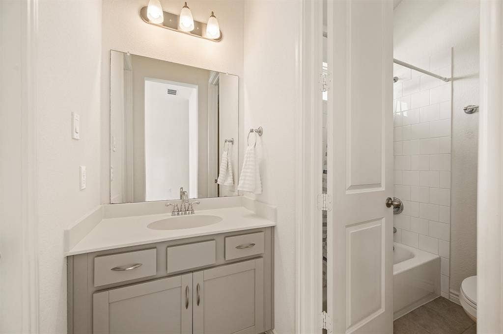 2900 Peekaboo Lane, Northlake, TX 76247 Light gray vanity with brushed nickel hardware, white countertop, and integrated sink that has a Jack and Jill bathroom.