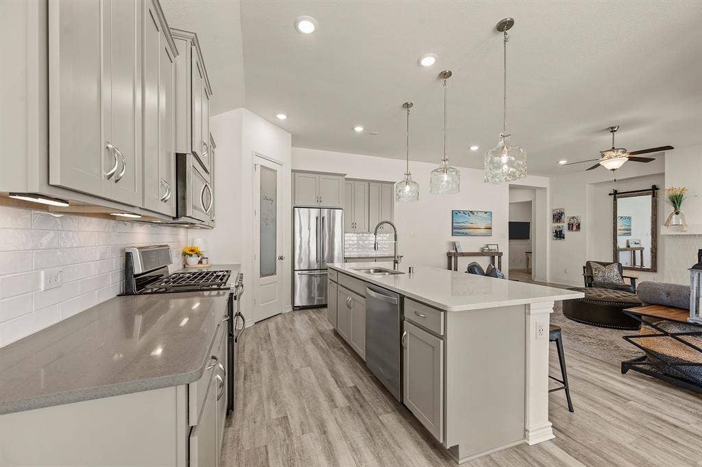 2900 Peekaboo Lane, Northlake, TX 76247 Open-concept kitchen featuring so much cabinetry so you will have plenty of storage, stainless steel appliances including a gas stove, a large island with quartz & beautiful pendant lighting,