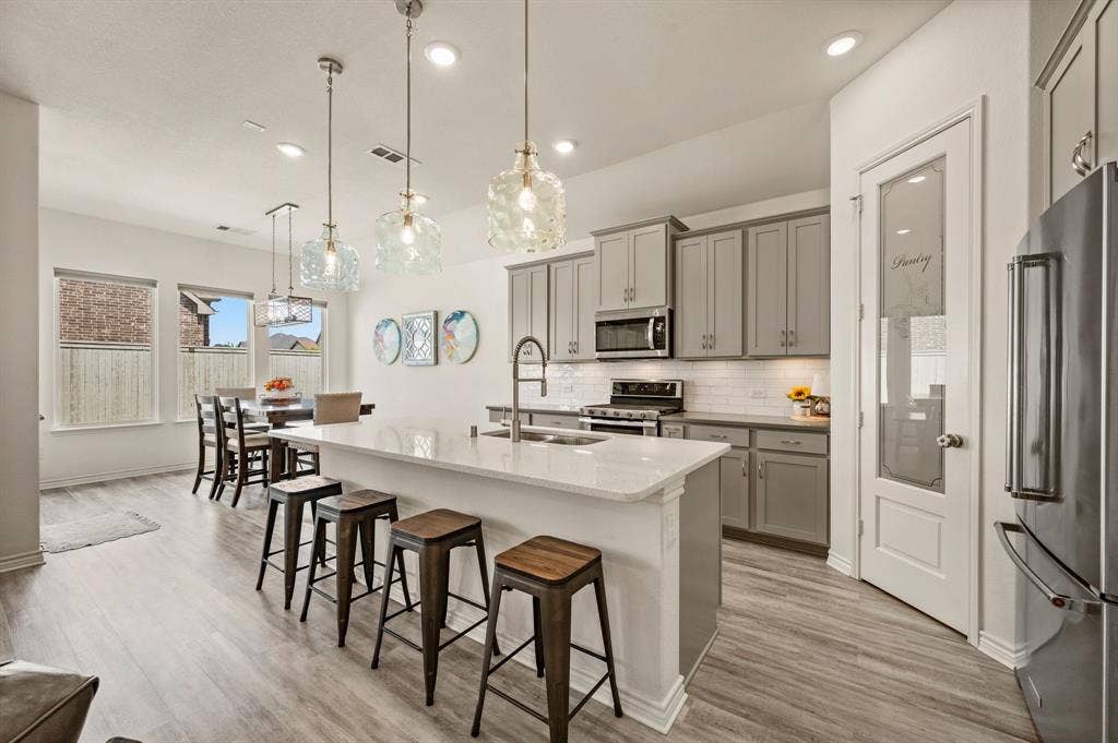 2900 Peekaboo Lane, Northlake, TX 76247 Open-concept kitchen featuring a wonderful island with seating, lots of cabinetry, stainless steel appliances, and LTV flooring.