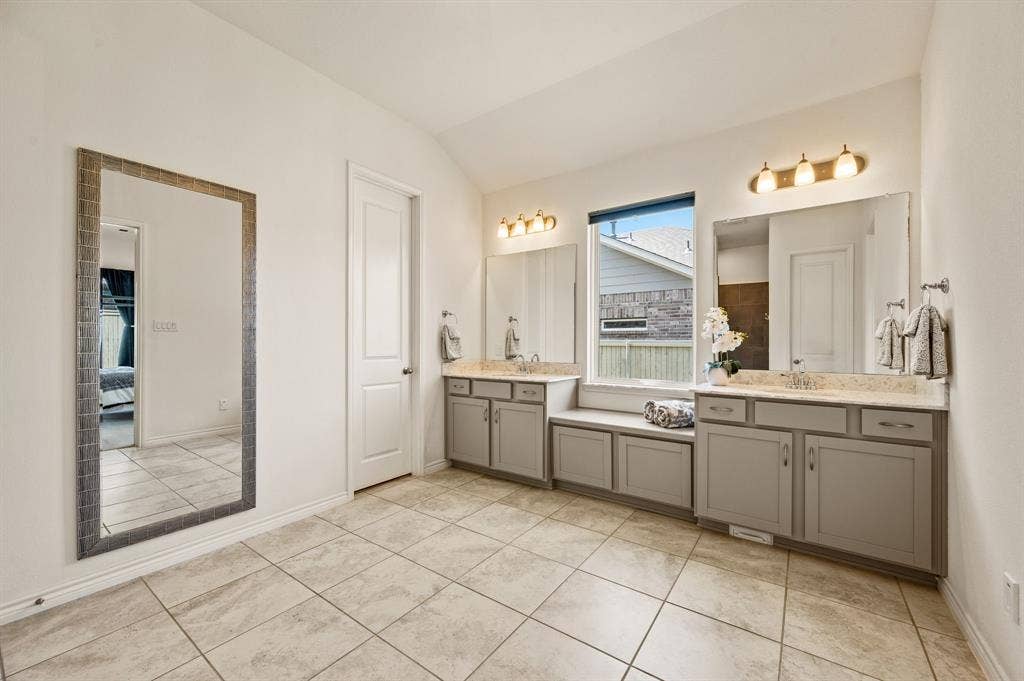 2900 Peekaboo Lane, Northlake, TX 76247 Primary bathroom with dual vanities and lots of cabinets for great storage, really beautiful tile flooring, and a window for natural light. This bathroom gives you room to move about and not be right next to each other!
