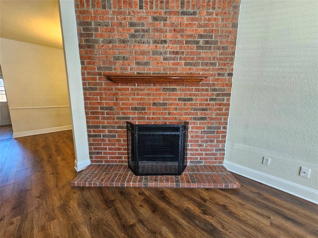 216 Samuel Boulevard, #j3, Coppell, TX 75019 Brick-clad fireplace with a wood mantelpiece and hearth, featuring wood-finish flooring