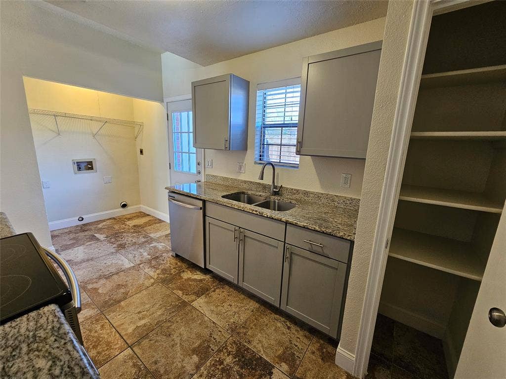 216 Samuel Boulevard, #j3, Coppell, TX 75019 Granite-style countertops, stainless-steel dishwasher, gray shaker-style cabinetry, a built-in pantry with shelving, and multi-toned tile flooring