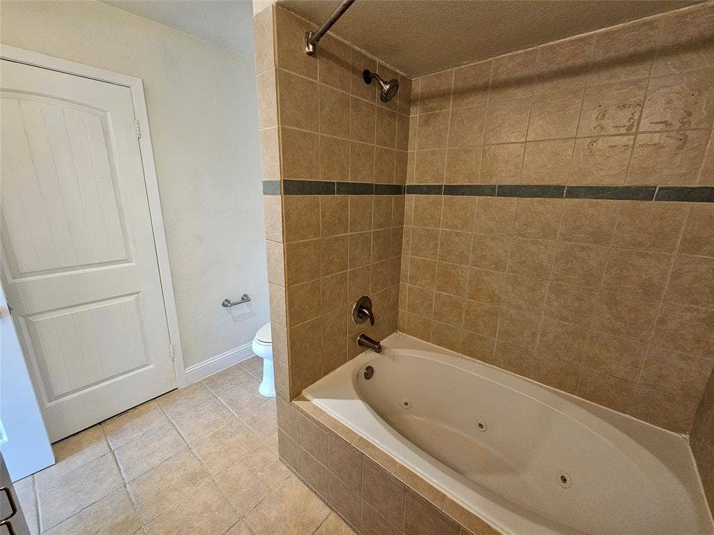 216 Samuel Boulevard, #j3, Coppell, TX 75019 Built-in jetted tub with tiled surround, tile flooring, and a white paneled door