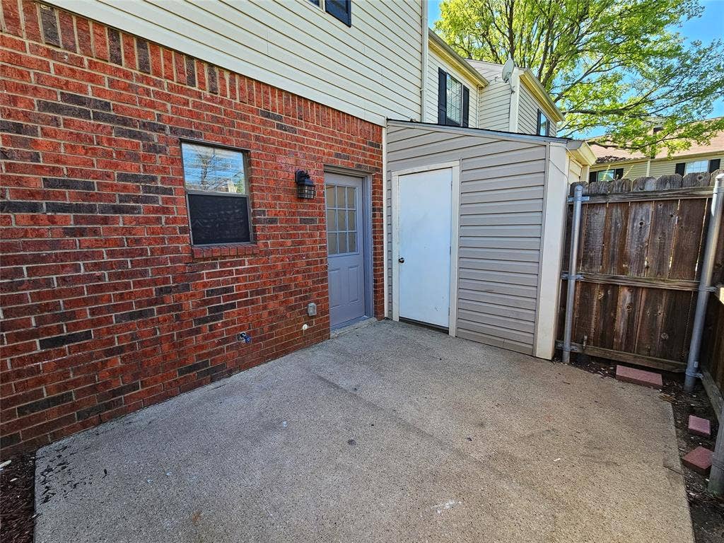 216 Samuel Boulevard, #j3, Coppell, TX 75019 Brick exterior with a concrete patio, featuring an attached storage shed with siding
