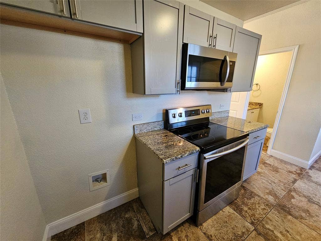 216 Samuel Boulevard, #j3, Coppell, TX 75019 Stainless steel microwave, electric range, and granite countertops complement the gray cabinetry