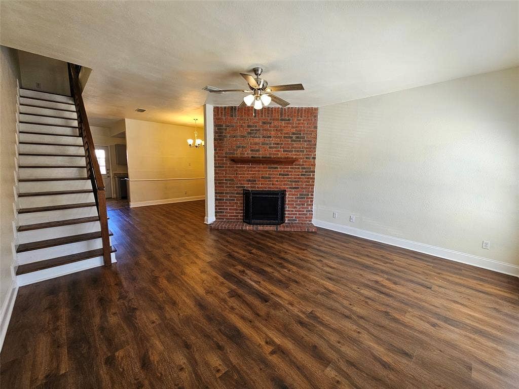216 Samuel Boulevard, #j3, Coppell, TX 75019 Wood-finish flooring throughout, featuring a brick fireplace with a wood mantel, an integrated ceiling fan with lighting, and a staircase with wood railing
