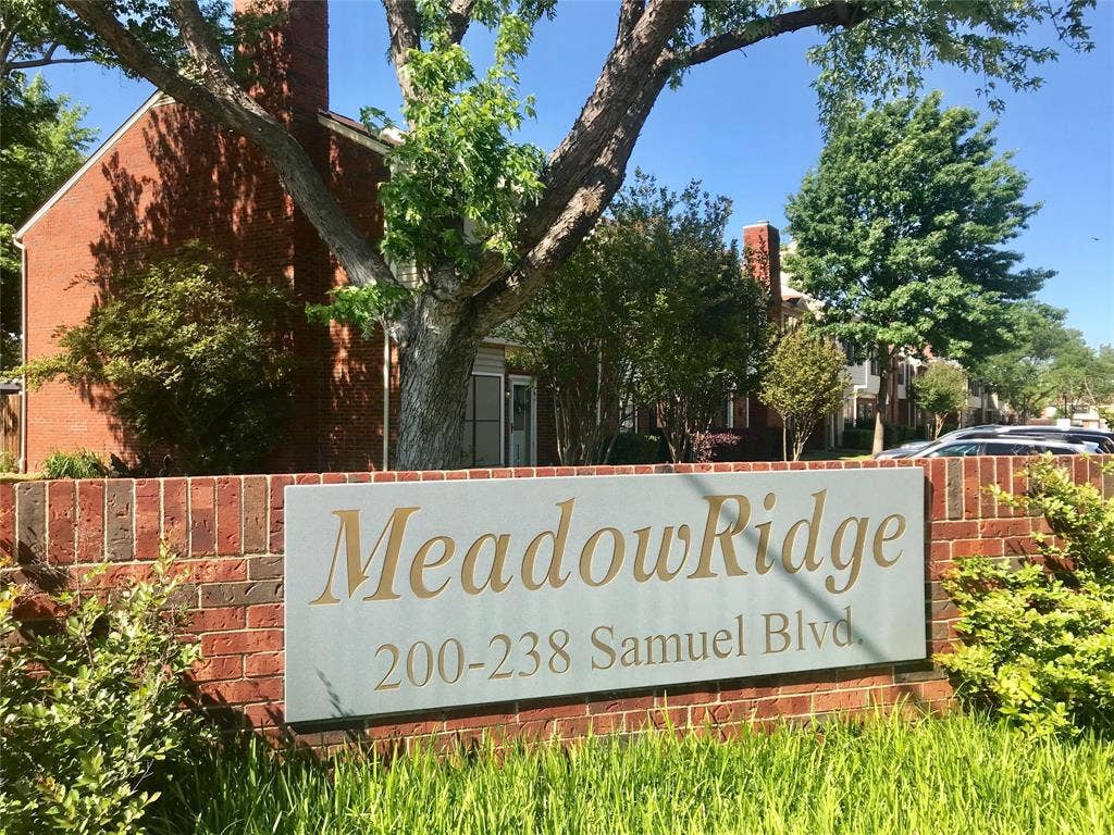 216 Samuel Boulevard, #j3, Coppell, TX 75019 Brick entryway wall with a prominent community sign, featuring established landscaping and mature trees