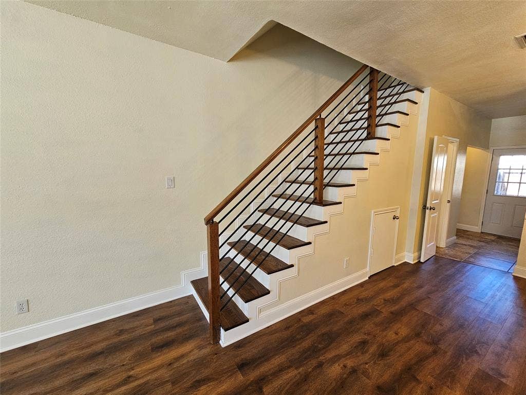 216 Samuel Boulevard, #j3, Coppell, TX 75019 Wood-finish flooring, staircase with dark wood treads, metal balusters, and wood handrail, white trim, and a white entrance door with decorative glass