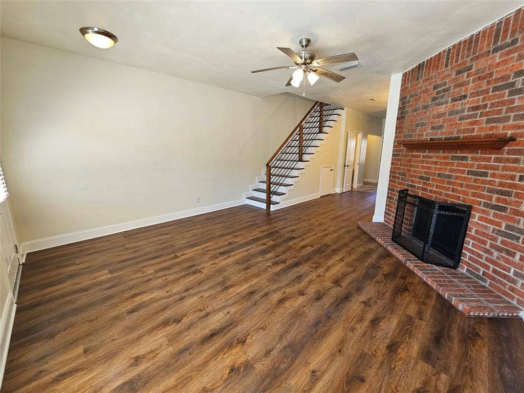 216 Samuel Boulevard, #j3, Coppell, TX 75019 Wood-finish flooring throughout, brick fireplace with a wood mantle, ceiling fan, and staircase with metal balusters