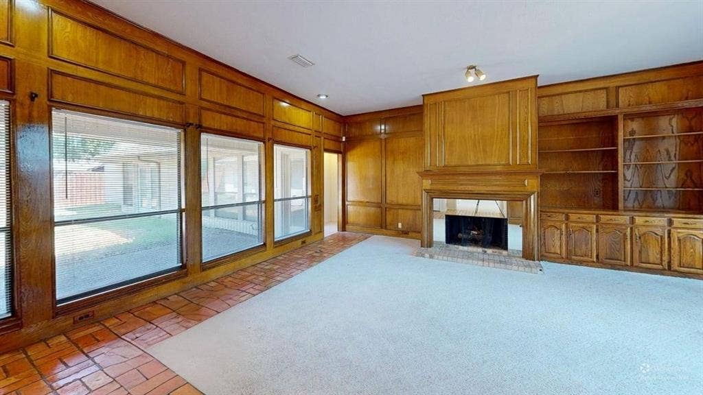 3717 Atrium Drive, Plano, TX 75075 Wood paneling, built-in shelving, built-in cabinetry, brick fireplace, and large windows